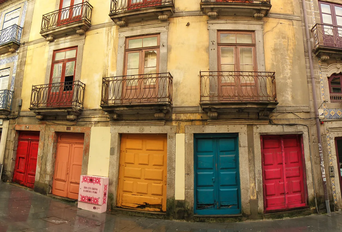 Pedestrians strolling past flower stalls and cafe terraces on Rua das Flores in Porto city centre